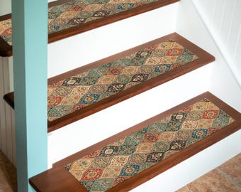 Puede incluir: Peldaños de escalera con un diseño estampado en tonos beige, rojo, azul y verde. Las huellas son rectangulares con un borde marrón oscuro, instaladas en escaleras blancas. El diseño presenta un patrón intrincado y repetitivo.