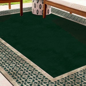 May include: A dark green outdoor rug with a white and green geometric border. The rug is made of a durable material and is perfect for protecting your patio or deck from dirt and grime.