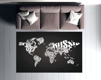 May include: A black and white world map rug with the names of countries and continents spelled out in white text. The rug is on a white wood floor in front of a gray couch.