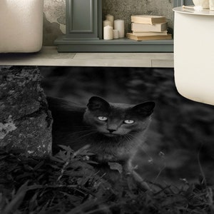 May include: A black cat with green eyes peeks out from behind a tree trunk in a dark, shadowy setting.