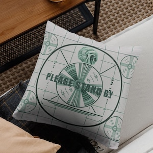 May include: A white throw pillow with a green and white television test pattern design. The pattern includes the text "PLEASE STAND BY".