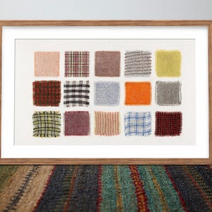 May include: A framed artwork featuring a collection of fabric swatches in various colors and patterns. The swatches are arranged in a grid, showcasing textures and designs. The frame is made of wood, and the artwork is displayed on a white background.