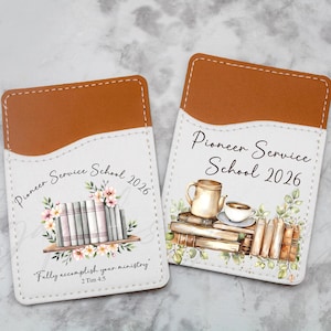 May include: Two white and brown cardholders with the text "Pioneer Service School 2026". One features books and flowers, the other a teapot and cup. The phrase "Fully accomplish your ministry" is also included.