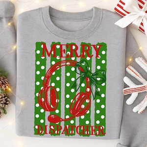 May include: A heather gray crewneck sweatshirt featuring a graphic print of red headphones with a green bow, set against a background of green vertical stripes with white polka dots. The text MERRY DISPATCHER is printed in red block letters.