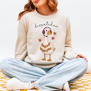 Puede incluir: Taza de cerámica blanca con asa negra y la frase "But First, Coffee" en negro. La taza se muestra sobre un fondo borroso, sugiriendo un ambiente acogedor.