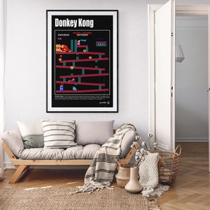 May include: A black and white poster with the title "Donkey Kong" and a pixelated image of the classic video game. The poster is framed and hanging on a white wall in a living room.