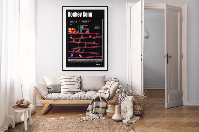 May include: A black and white poster with the title "Donkey Kong" and a pixelated image of the classic video game. The poster is framed and hanging on a white wall in a living room.