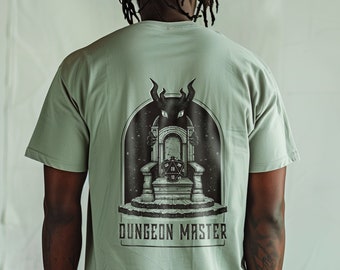 May include: A sage green t-shirt with a black graphic of a throne with a dragon on it. The text "Dungeon Master" is printed below the graphic.