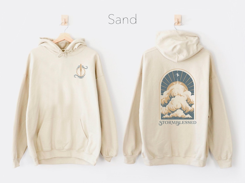 May include: Sand colored hoodie with a graphic of a cloud with the text "Stormblessed" on the back and a small graphic on the front.