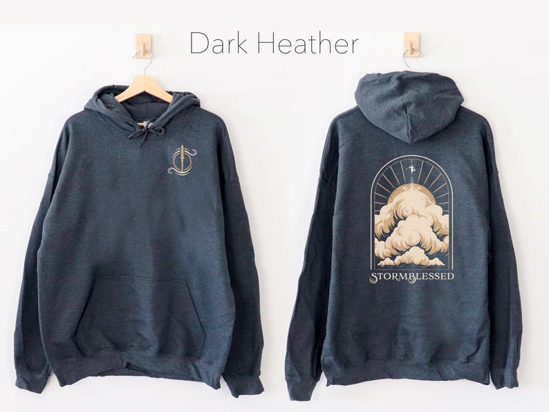May include: A dark heather grey hoodie with a graphic of a stylized cloud with the text "STORMBLESSED" on the back. The front of the hoodie has a small graphic of a stylized sword.