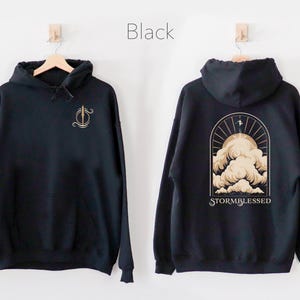 May include: Black hoodie with a gold graphic of a cloud and the text "STORMBLESSED" on the back. The front of the hoodie has a gold graphic of a sword.