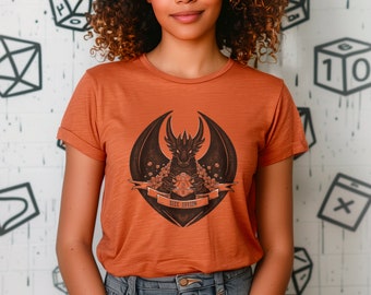 May include: A rust-colored t-shirt with a black dragon graphic holding a 20-sided die. The dragon is surrounded by flowers and the text "Dice Dragon" is below the dragon.