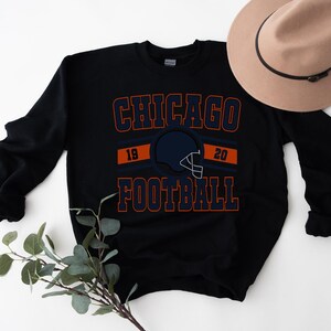 May include: Black sweatshirt with a navy blue and orange graphic that says "CHICAGO FOOTBALL" with a football helmet and the numbers 19 and 20.