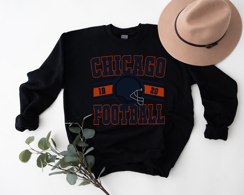 May include: Black sweatshirt with a navy blue and orange graphic that says "CHICAGO FOOTBALL" with a football helmet and the numbers 19 and 20.