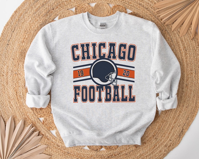 May include: Gray sweatshirt with a navy blue and orange graphic that says "CHICAGO FOOTBALL" with a football helmet in the center and the numbers "19" and "20" on either side of the helmet.