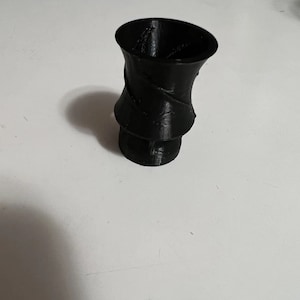 May include: A black, 3D printed vase with a swirling design.