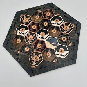 May include: A wooden hexagonal game board with a black background and various colored hexagonal tiles. The tiles feature numbers, images of sheep, wheat, trees, and a camel. The board is designed for a game.