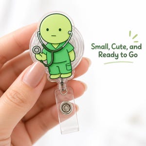 Puede incluir: Un portatarjetas de acrílico transparente con un personaje de dibujos animados de piel verde claro que viste uniforme médico verde y un estetoscopio. El personaje sostiene un estetoscopio. El texto Small, Cute, and Ready to Go aparece al lado.