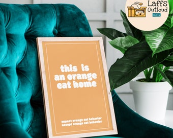 May include: A framed print with an orange background and white text that reads "this is an orange cat home" and "expect orange cat behavior accept orange cat behavior".