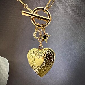 May include: A gold necklace with a heart-shaped locket, a small star charm, and a toggle clasp.