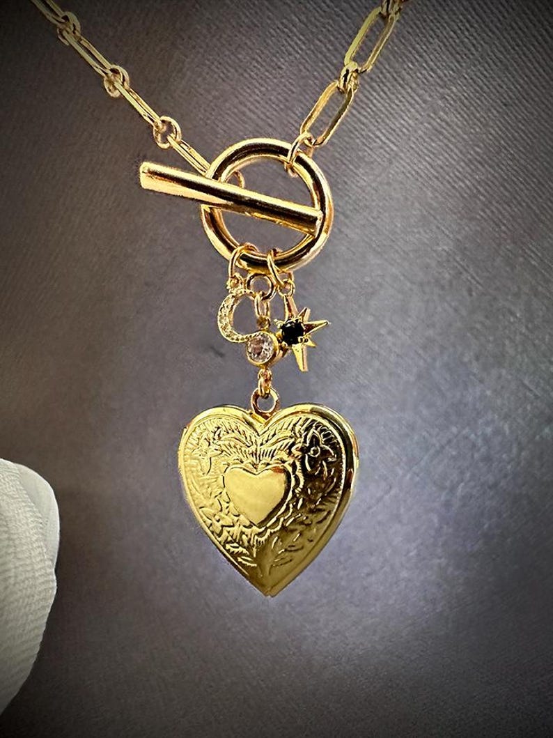 May include: A gold necklace with a heart-shaped locket, a small star charm, and a toggle clasp.