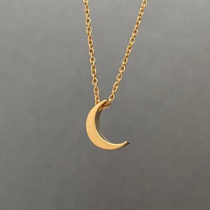 Puede incluir: Un collar de cadena dorada con un colgante de media luna.