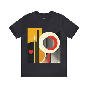 May include: A dark grey t-shirt with a geometric design featuring a large circle with a red ring, a smaller red circle, and yellow, black, and grey shapes.