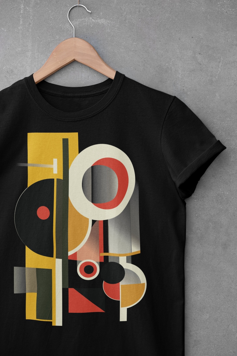 May include: Black t-shirt with a geometric design featuring circles, squares, and rectangles in shades of yellow, red, black, and gray.