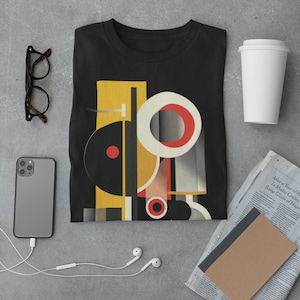 May include: A black t-shirt with a geometric design featuring circles, squares, and rectangles in yellow, red, and white. The design is reminiscent of abstract art.