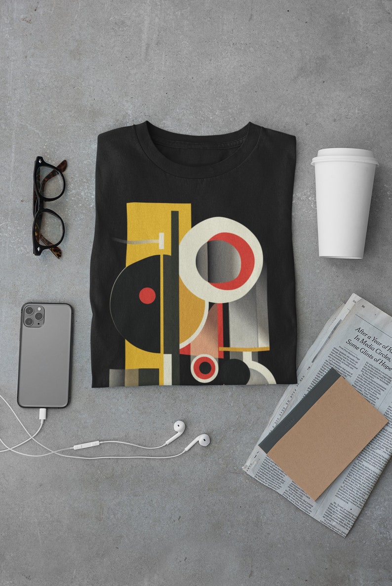 May include: A black t-shirt with a geometric design featuring circles, squares, and rectangles in yellow, red, and white. The design is reminiscent of abstract art.