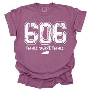May include: A mauve t-shirt with a white distressed graphic of the number 606 and the text "home sweet home" with a white outline of the state of Kentucky.