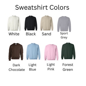May include: Image displaying eight crewneck sweatshirts in various colors: white, black, sand, sport grey, dark chocolate, light blue, light pink, and forest green. Each sweatshirt is labeled with its respective color name.