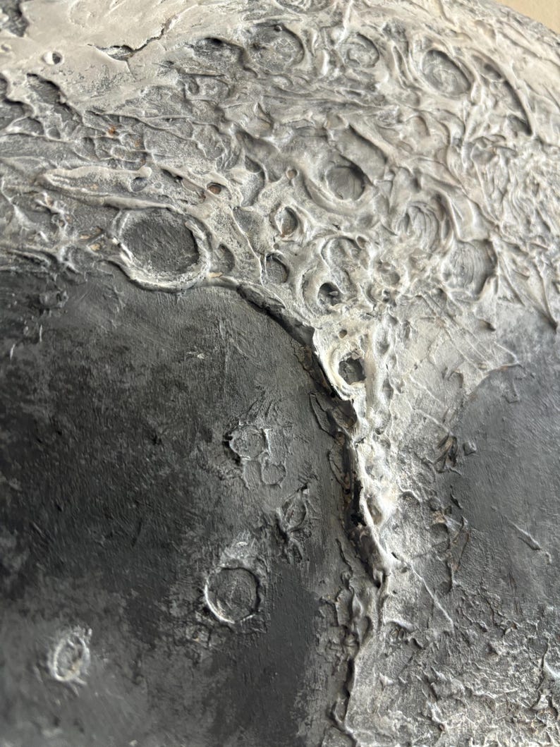 Peut inclure: Gros plan sur une surface textur&eacute;e, grise et noire, avec une texture rugueuse et irr&eacute;guli&egrave;re. La surface pr&eacute;sente une vari&eacute;t&eacute; de crat&egrave;res et d'indentations, ressemblant &agrave; la surface de la lune.