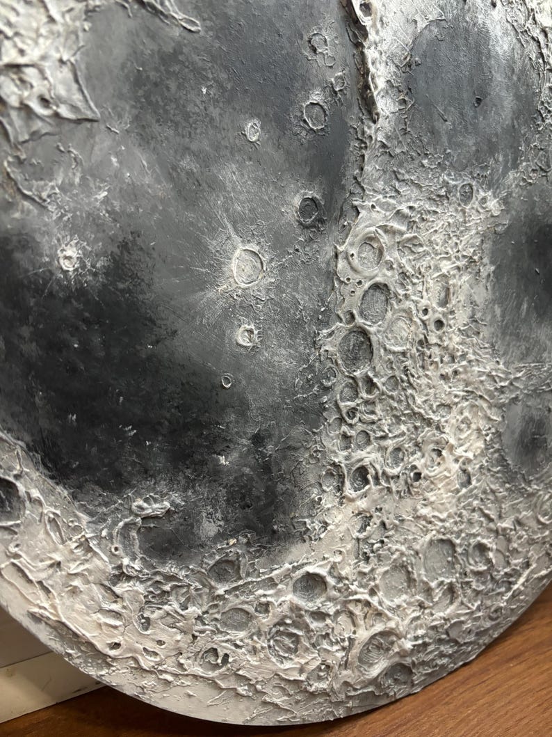 Peut inclure: Gros plan d'une sculpture ronde de lune textur&eacute;e en gris et blanc. La surface de la lune est textur&eacute;e pour ressembler aux crat&egrave;res et &agrave; la surface de la lune.