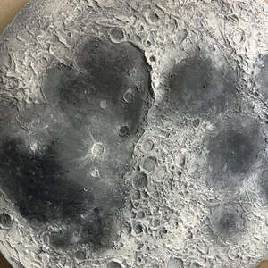 Peut inclure: Gros plan d'un objet en forme de lune gris et blanc avec une surface textur&eacute;e. L'objet est fait pour ressembler &agrave; la lune avec des crat&egrave;res et d'autres caract&eacute;ristiques de surface.