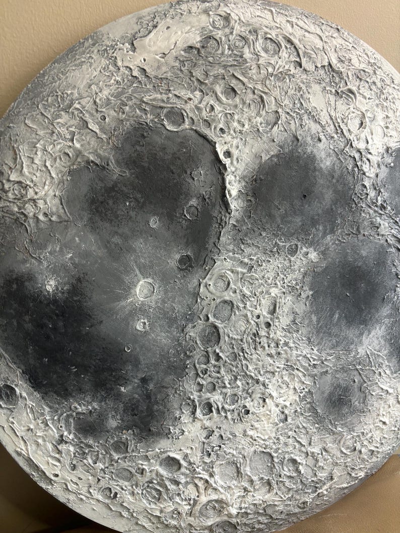 Peut inclure: Gros plan d'un objet en forme de lune gris et blanc avec une surface textur&eacute;e. L'objet est fait pour ressembler &agrave; la lune avec des crat&egrave;res et d'autres caract&eacute;ristiques de surface.