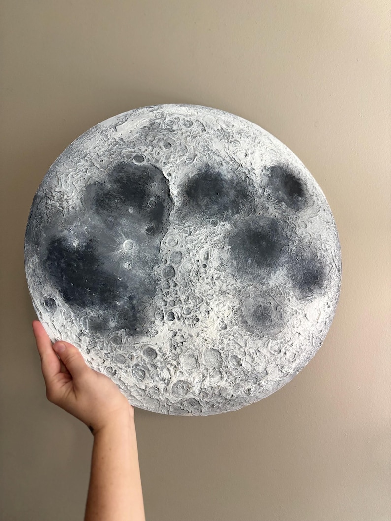 Peut inclure: Une lune peinte en blanc et gris avec une surface textur&eacute;e, ressemblant &agrave; la surface de la vraie lune.