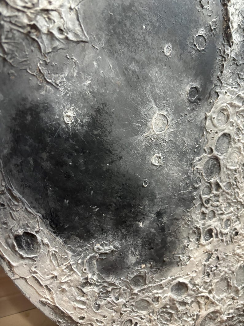 Peut inclure: Gros plan sur une surface textur&eacute;e grise et blanche ressemblant &agrave; la surface de la lune. La surface pr&eacute;sente des crat&egrave;res et une texture rugueuse et irr&eacute;guli&egrave;re.