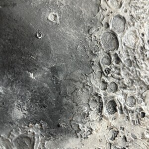 Peut inclure: Gros plan sur une surface textur&eacute;e, grise et blanche ressemblant &agrave; la surface de la lune. La surface pr&eacute;sente de nombreux crat&egrave;res et une texture rugueuse et irr&eacute;guli&egrave;re.