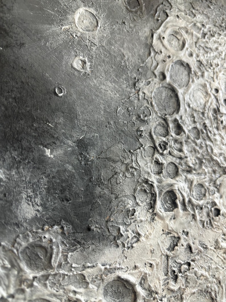 Peut inclure: Gros plan sur une surface textur&eacute;e, grise et blanche ressemblant &agrave; la surface de la lune. La surface pr&eacute;sente de nombreux crat&egrave;res et une texture rugueuse et irr&eacute;guli&egrave;re.