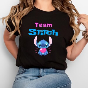 May include: Black t-shirt with the text "Team Stitch" in blue and pink. A blue Stitch character with a pink heart is below the text.