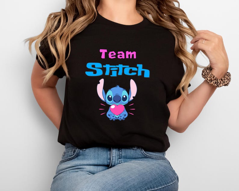 May include: Black t-shirt with the text "Team Stitch" in blue and pink. A blue Stitch character with a pink heart is below the text.