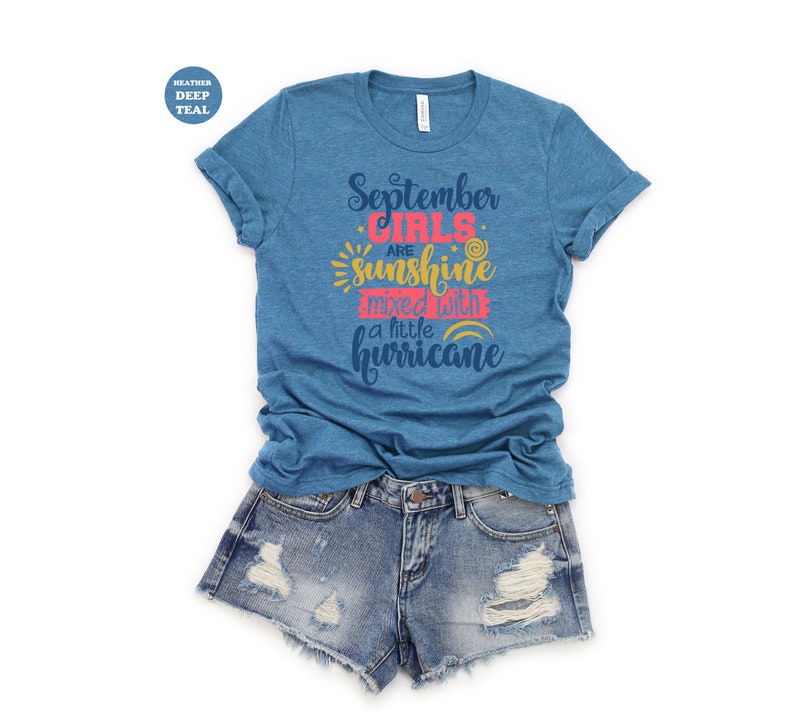 May include: A heather deep teal t-shirt with the text "September girls are sunshine mixed with a little hurricane" in a colorful font.