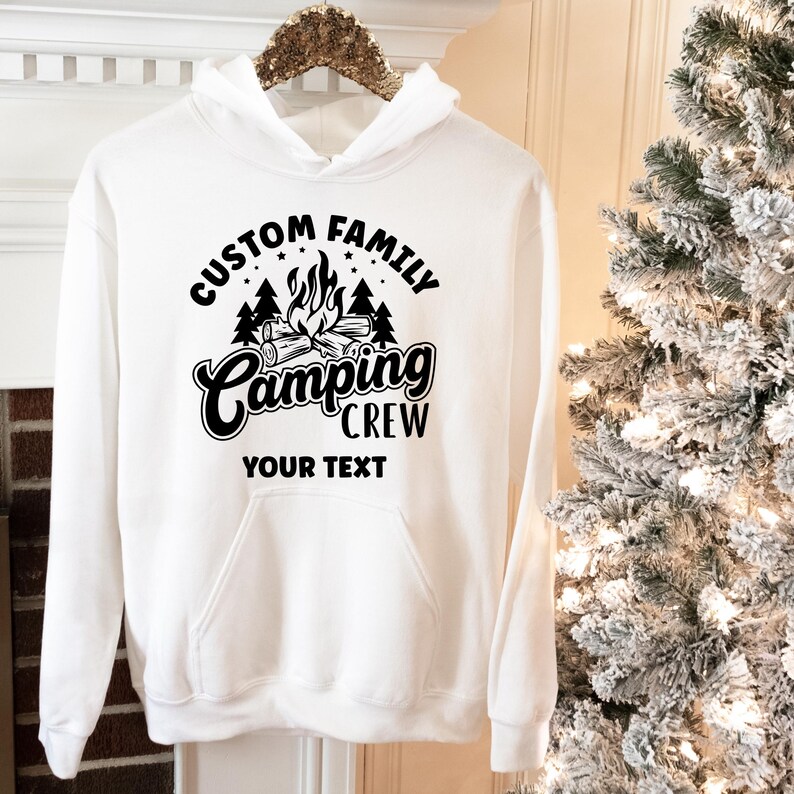 Pode incluir: Moletom branco com capuz com texto preto que diz "Custom Family Camping Crew" com um gr&aacute;fico de fogueira e as palavras "Your Text" abaixo.