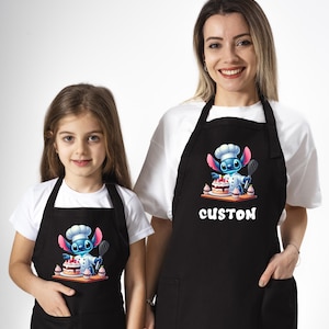 May include: Two black aprons featuring a blue Stitch character wearing a chef's hat and holding a cake. The aprons have a pocket at the bottom and the text "CUSTOM" is printed on the larger apron.