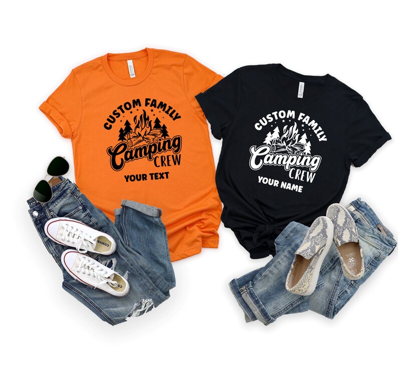 Pode incluir: Duas camisetas com tema de acampamento. A camiseta laranja tem texto preto que diz "Custom Family Camping Crew Your Text". A camiseta preta tem texto branco que diz "Custom Family Camping Crew Your Name". Ambas as camisetas apresentam um gr&aacute;fico de fogueira e &aacute;rvores.