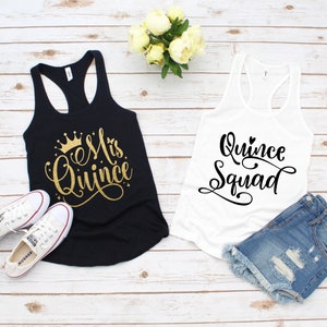 May include: Two tank tops, one black and one white, with text on the front. The black tank top says "Mis Quince" in gold glitter with a crown above the text. The white tank top says "Quince Squad" in black.