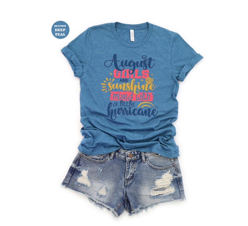 May include: A heather deep teal t-shirt with the text "August girls are sunshine mixed with a little hurricane" in pink, yellow, and blue lettering.