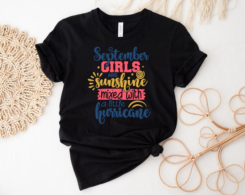 May include: Black t-shirt with the text "September Girls are sunshine mixed with a little hurricane" in colorful lettering.