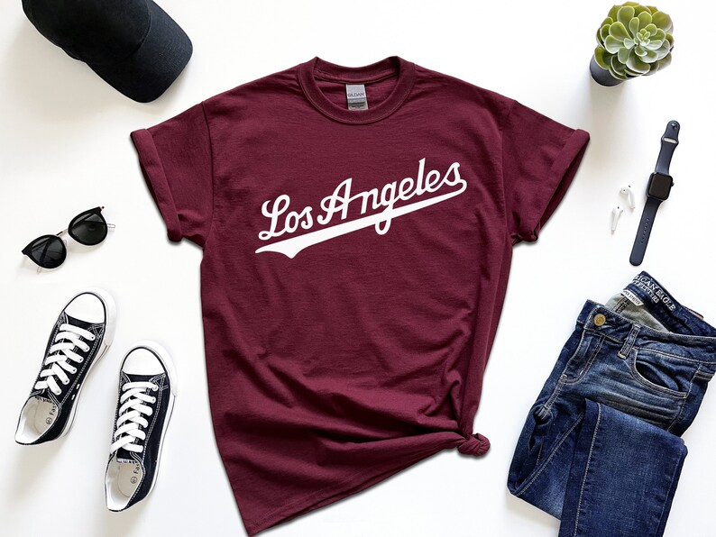 May include: A maroon t-shirt with a white graphic that says "Los Angeles" in a vintage baseball font.